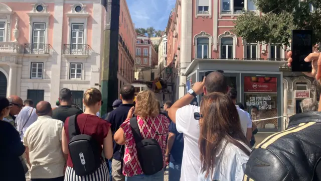 Onlookers take pictures of the site of the funicular crash in Lisbon