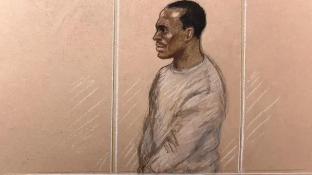 A court sketch of Hadush Kebatu wearing a grey sweatshirt standing behind glass panels