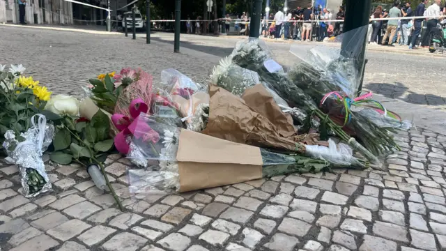 Flowers laid down on a cobbled street behind a police cordon