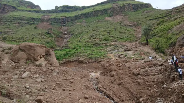 Two channels of dry mud down a steep incline with significant amounts of rock and earth at the bottom of the channels