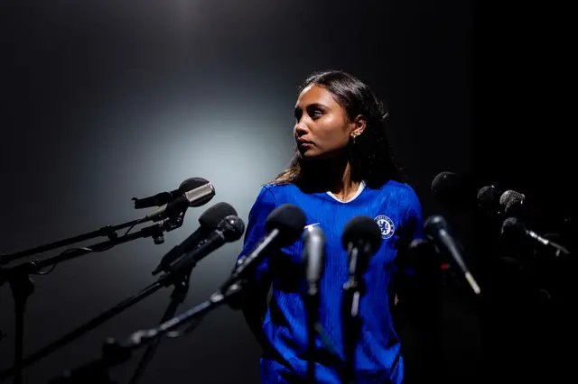 Alyssa Thompson poses in front of a faux press pack