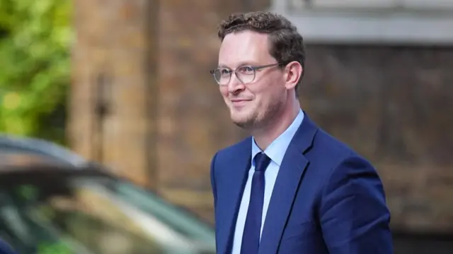 Man in navy blue suit and spectacles smiles