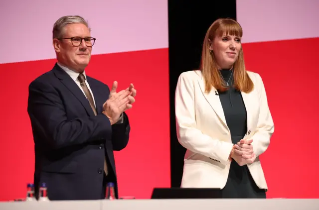 Keir Starmer, wearing a suit, applauds at the Labour party conference last year, with Angela Rayner standing at his side