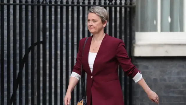 Woman in maroon suit walks down street