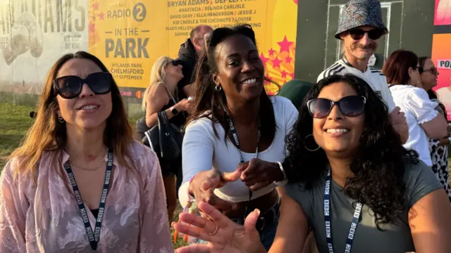 Sonia Watson, Akylah Rodriguez and Nadira Tudor dance in front of a camera. The women wear BBC ID badges and sunglasses.