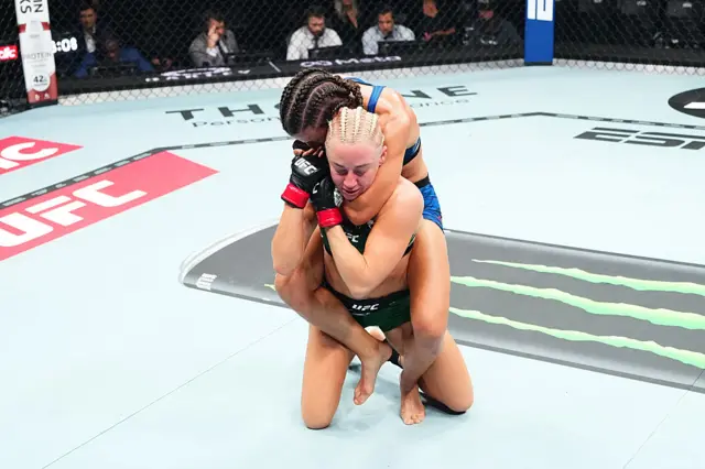 Sam Hughes with a choke hold on Shauna Bannon from behind