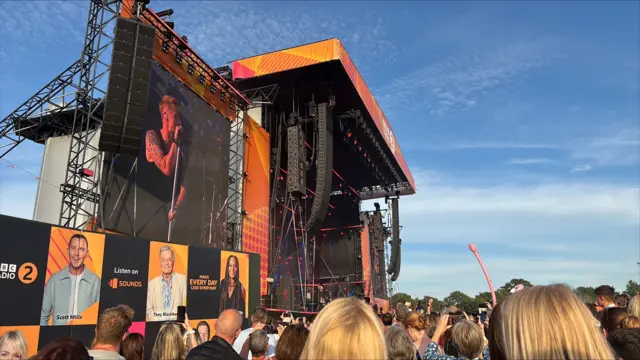 Ronan Keating performs on stage. A large crowd watches on.