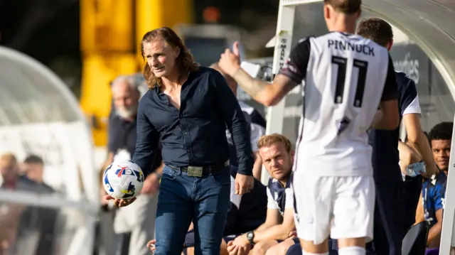 Gareth Ainsworth holds the ball in the dugout