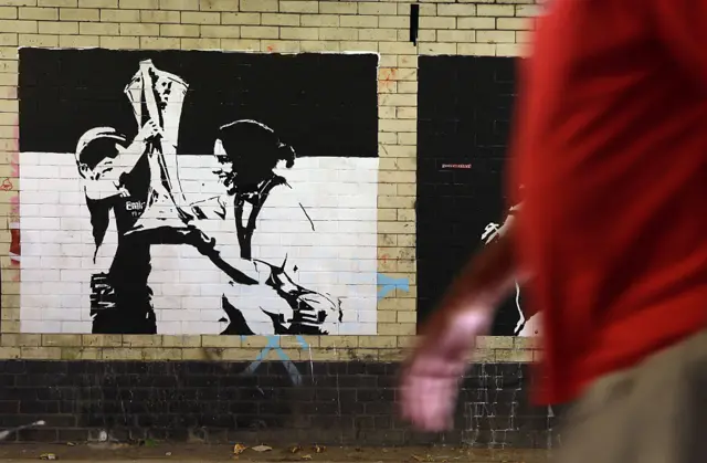 Mural of Arsenal boss Slegers lifting the UWCL trophy with her son near the Emirates