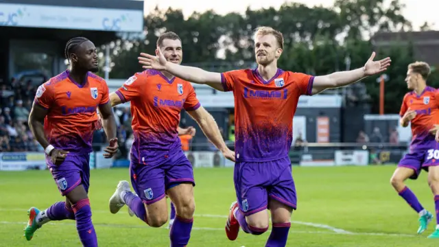 Max Clark holds his arms wide as he runs with two team-mates behind him