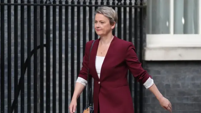 Yvette Cooper wears a burgundy blazer and walks toward 10 Downing Street.