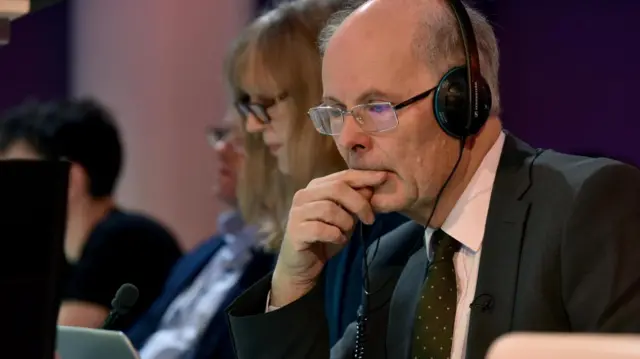 John Curtice wears headphones while looking at a laptop screen.