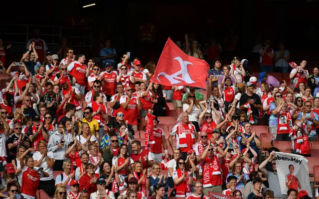 Arsenal fans wave flags and celebrate at full time