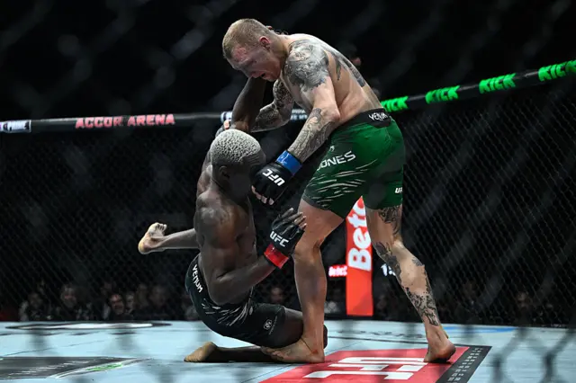 Oki falls to the canvas with Mason Jones standing over him