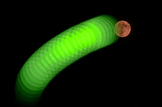 A red hued Moon in a night sky.