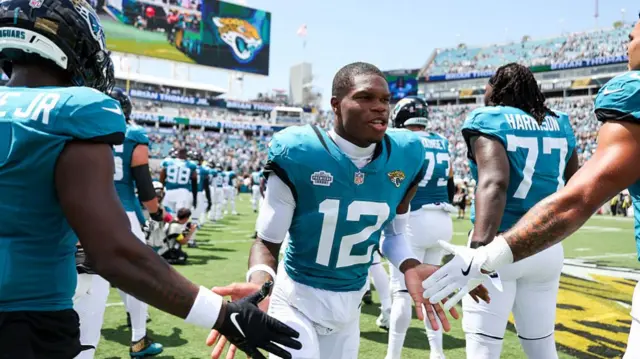 Travis Hunter is welcomed onto the field by his Jacksonville Jaguars team-mates before they play the Carolina Panthers
