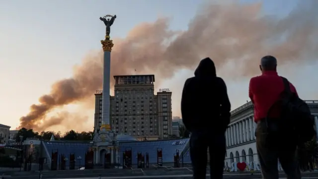 People look at smoke rise over a building of the Ukrainian government headquaters
