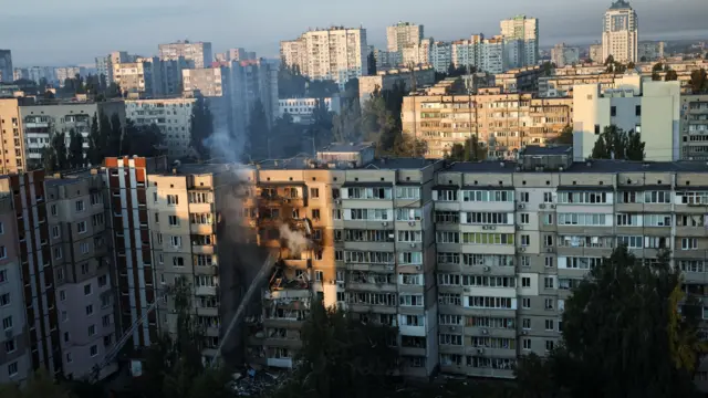 Emergency workers extinguish fire in an apartment building - a wide shot of the building and Kyiv skyline