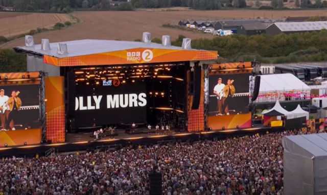 A drone image of a large stage with thousands of people in front of it.