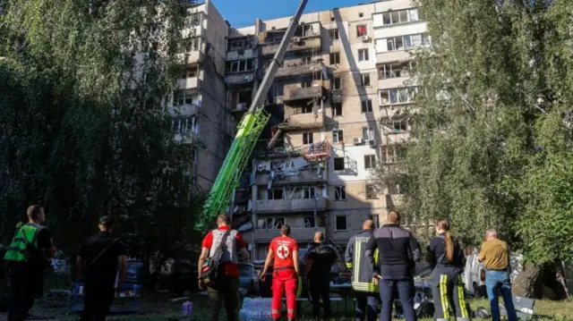 Ukrainian rescuers look at a damaged building in Kyiv.