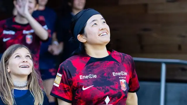 Fuka Tsunoda #14 of the Urawa Red Diamonds walks out to the field with a fan before an international friendly match between Bay FC and the Urawa Red Diamonds on July 27, 2025 at PayPal Park in San Jose, CA.
