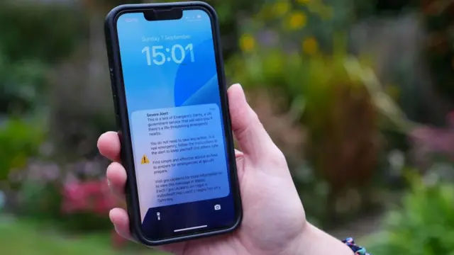 A person holding a mobile phone with an alarm during a national emergency alert test