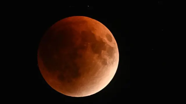 A view of the moon, which red-tinted craters visiible