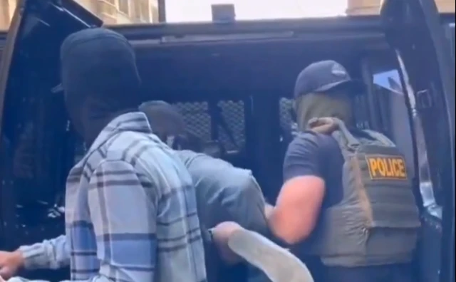 A screengrab from a video showing ICE agents putting a person into an SUV - the footage is from Chicago but was taken in June