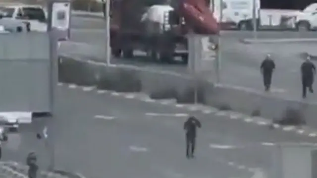 A screengrab from a verified video showing men running across Golda Me’ir Boulevard in Jerusalem