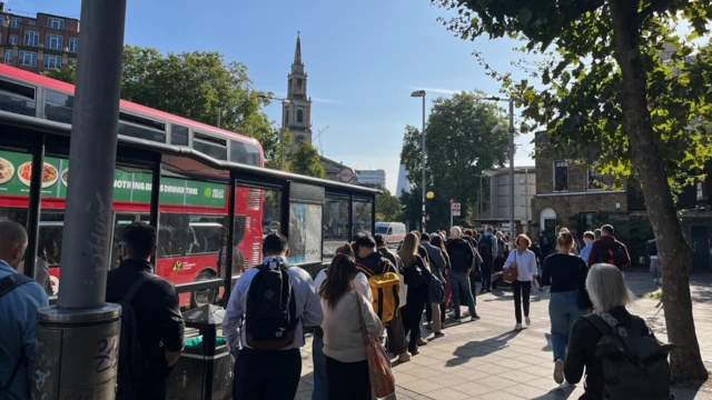 A long line of people queuing for a bus