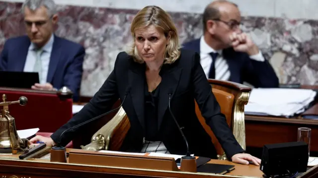 President of the French National Assembly Yael Braun-Pivet sits in French parliament wearing a black blazer.
