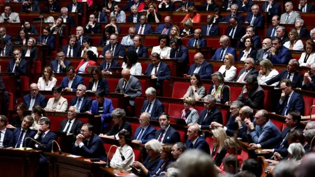 Members of parliament sit on red seats in France's National Assembly in formalwear.