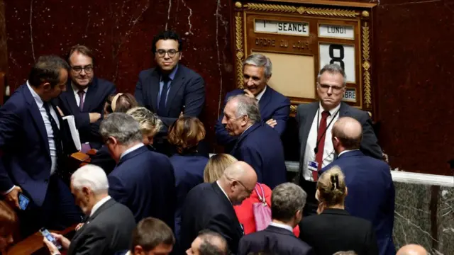 Prime Minister Francois Bayrou leaves National Assembly surrounded by lawmakers.