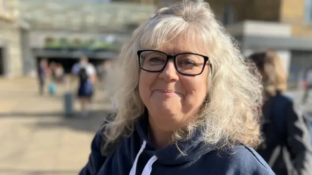 Rachel Edwards, an elderly woman with big white hair and big black glasses smiles.