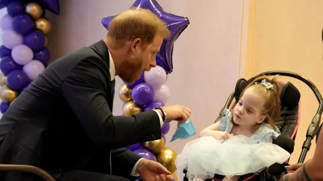 Prince Harry playing a game with a girl in a light blue dress