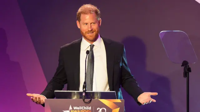 Prince Harry making a speech with a purple background