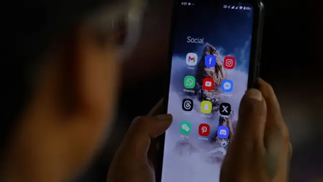 An extreme close-up of a person, with his back to the camera, holding a phone screen close to his face