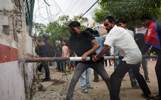 Demonstrators attempt to break an outer wall of the Parliament complex