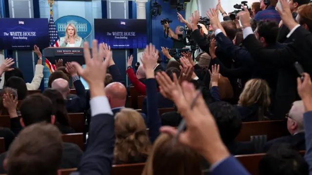 Journalists raise their hands to ask questions, as White House Press Secretary Karoline Leavitt speaks during a press briefing