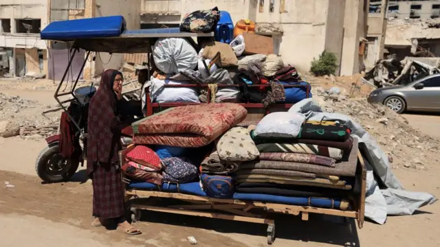 Palestinian woman is seen carrying her belongings in Gaza City