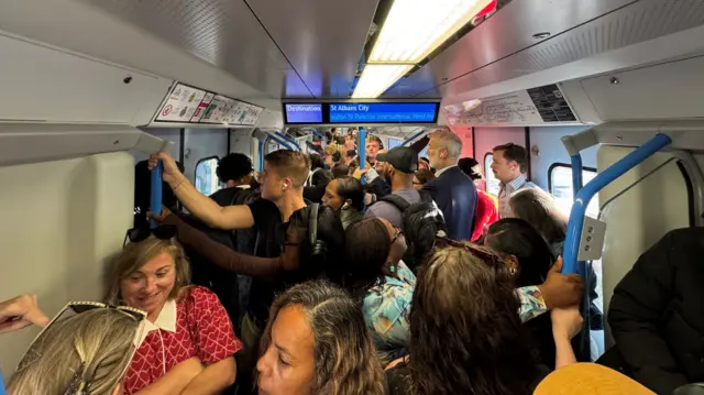 Packed train with people standing crammed into the carriage