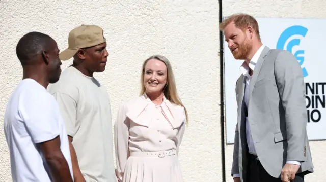 Prince Harry in a grey jacket next to a woman and two men