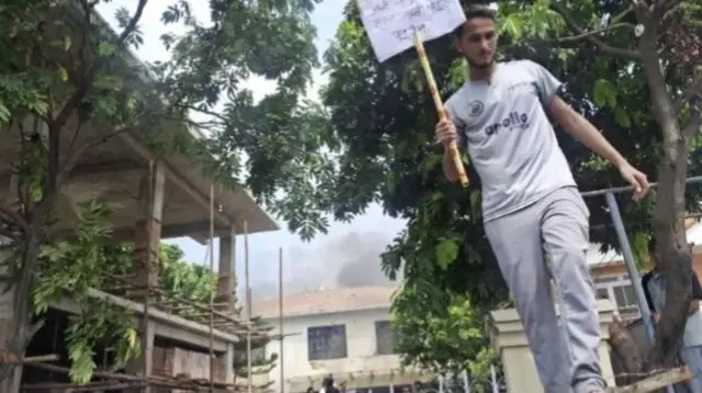 A man holds a placard near the home of the former prime minister