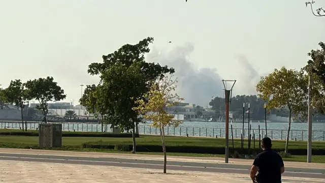 Smoke is seen rising on the other side of a river in Qatar