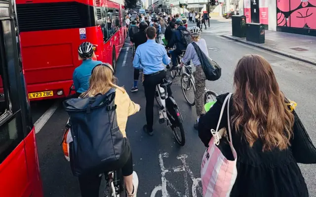 People in a queue on bikes next to a London bus