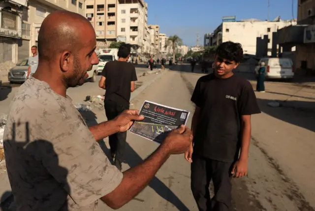 A man holding a leaflet showing the evacuation notice map