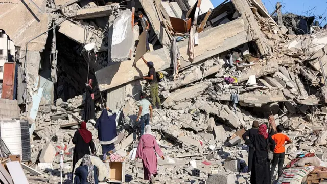 People climbing about in a huge pile of rubble from a struck building