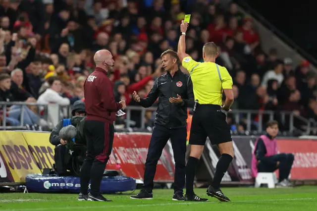 Referee Robert Jones shows Canada boss Jesse Marsch a yellow card