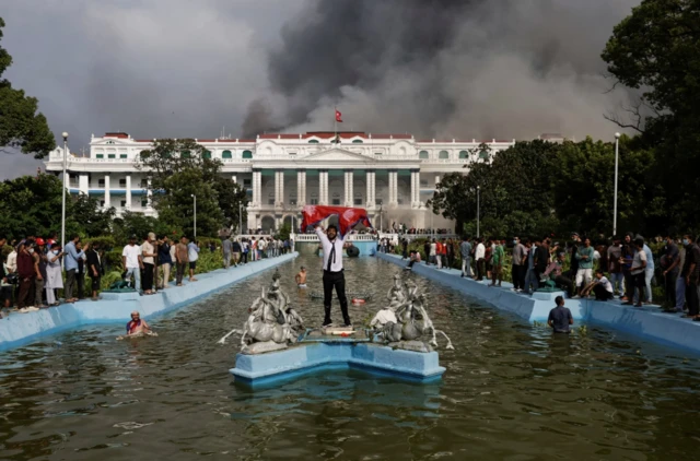 A demonstrator holding Nepal's flag celebrates at the Singha Durbar office complex that houses the Prime Minister's office and other ministriers