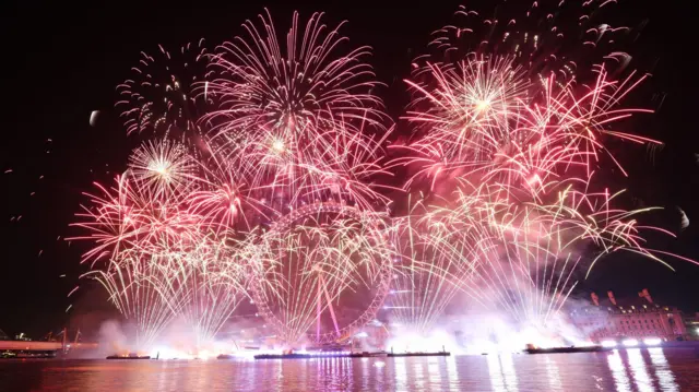 Red fireworks explode around the London Eye